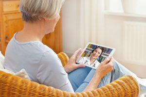 old woman with tablet pc during an online consultation with her doctor in her living room